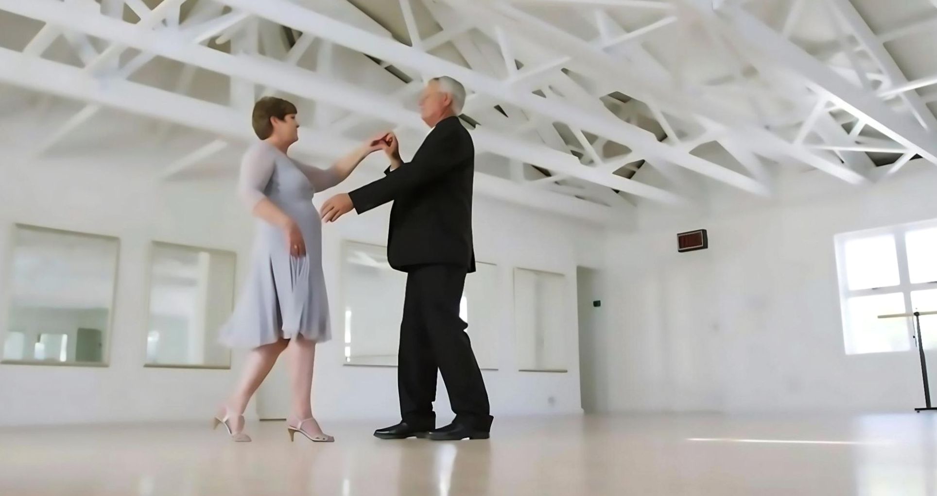 Two dancers practising partner dancing footwork in a studio
